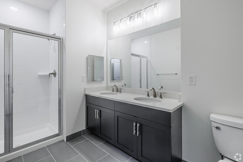 Master bath with dual-sink quartz vanity and glass-enclosed shower
