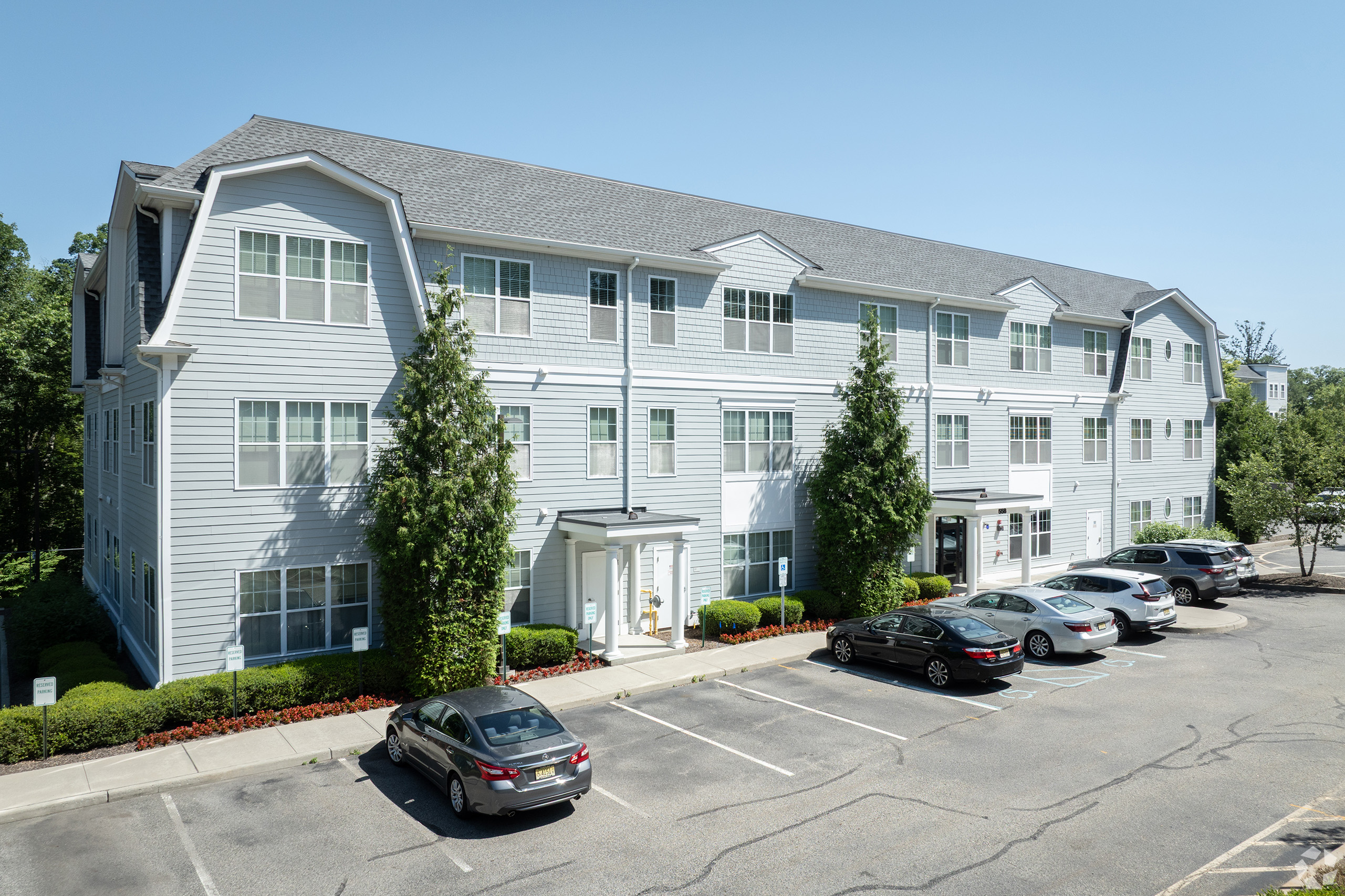 Colonial Pointe Luxury building at 558 Colonial Road with gambrel-roof architecture, columned portico entrance, and reserved outdoor parking